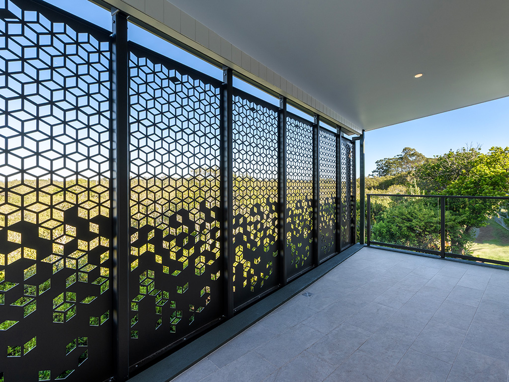 outdoor covered balcony at Assisi apartments with decorative screening panels overlooking tree canopy