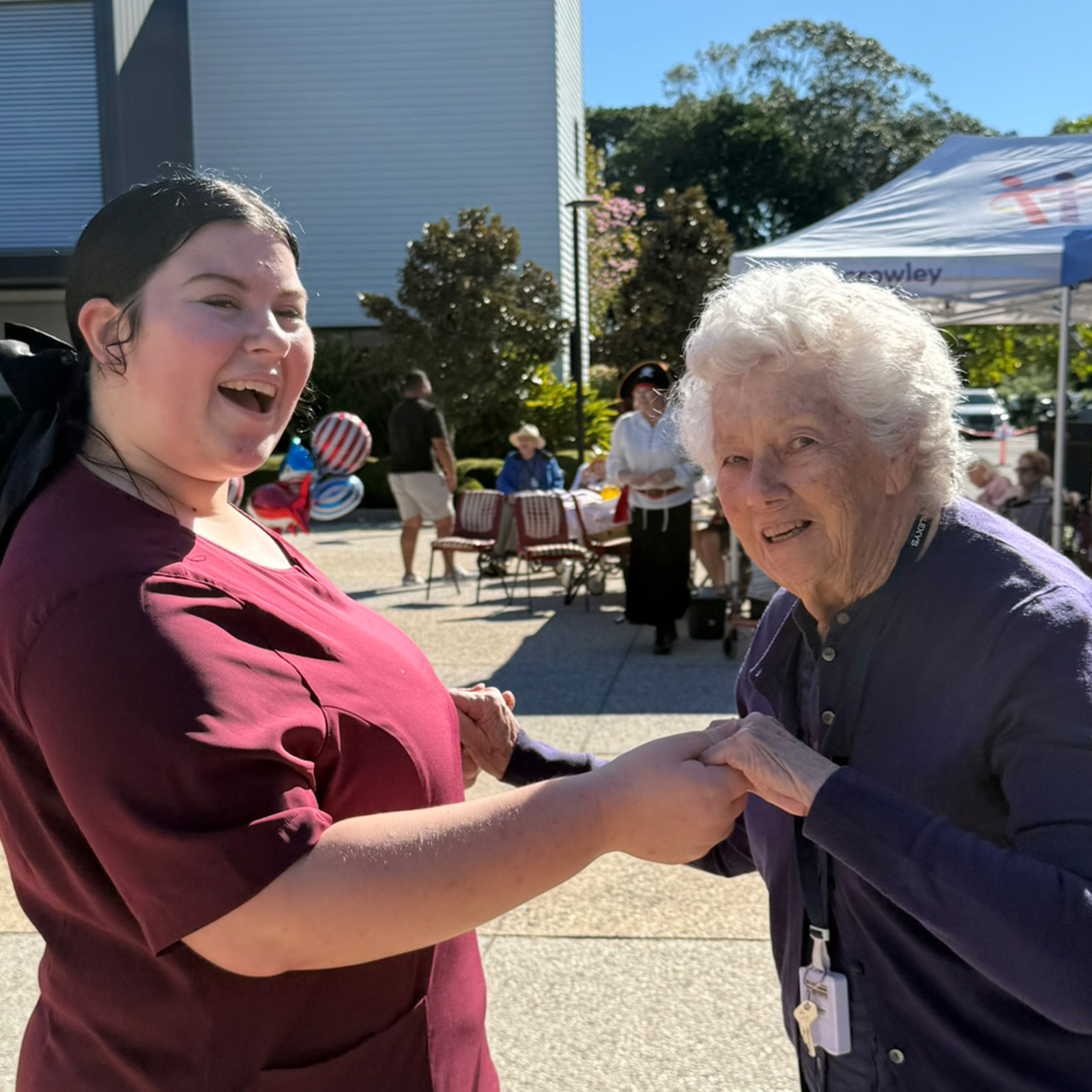 smiling staff and resident dancing outdoors in the plaza