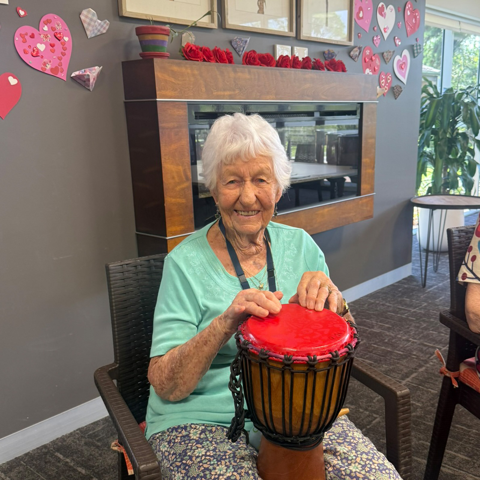 Res Care Drumming smiling resident using a bongo drum during an activity